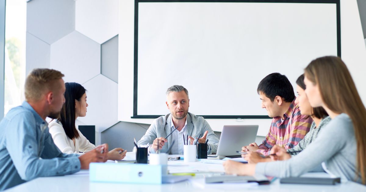 Business owner together with his employee discussing what is virtual profit sharing in a table with white board