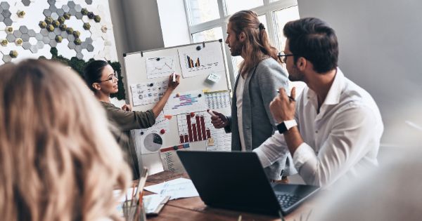 A business meeting with a woman business owner writing on a board about business strategy and innovation