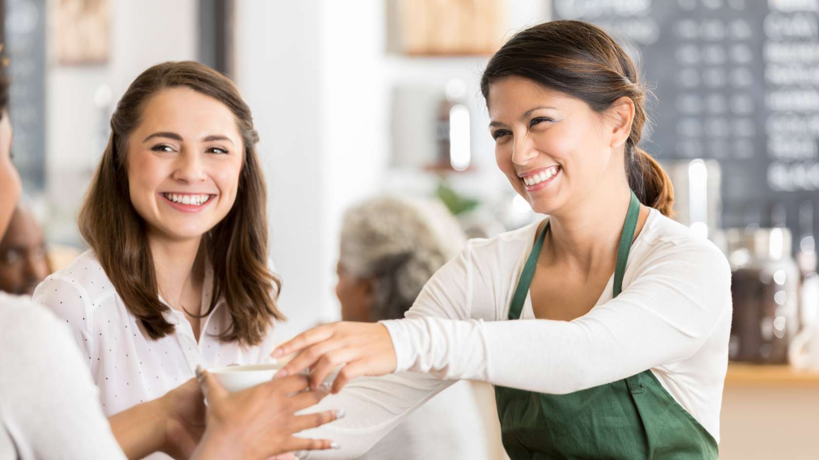 Owner of coffee shop handling a coffee order in a satisfied customer