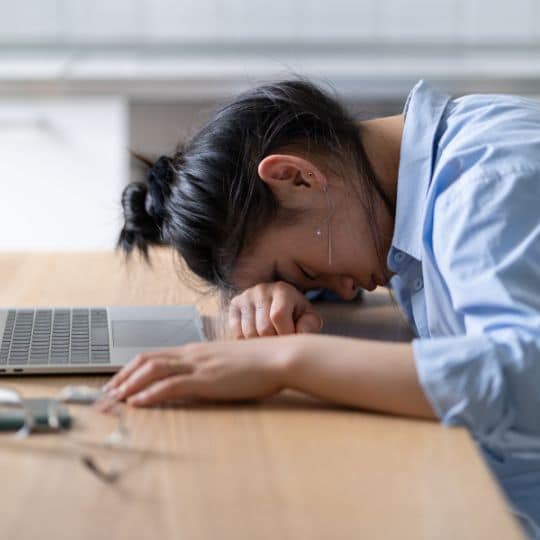 man employee with hands in his chin thinking in a table with notebook and coffee