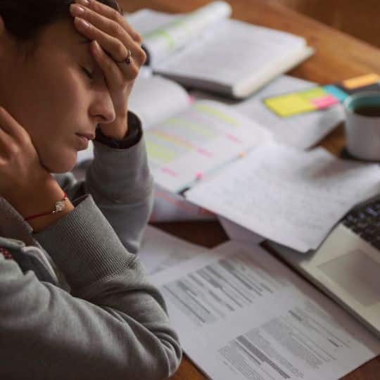 man employee with hands in his chin thinking in a table with notebook and coffee