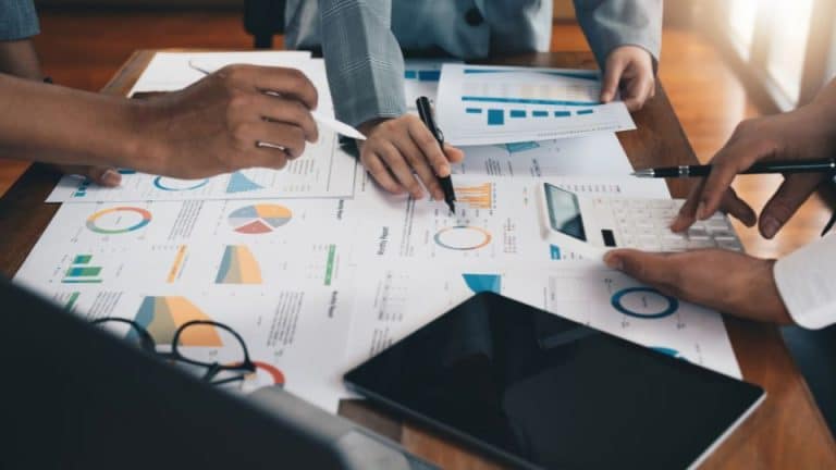Business strategy papers spread out in a table with business owners hands pointing at them