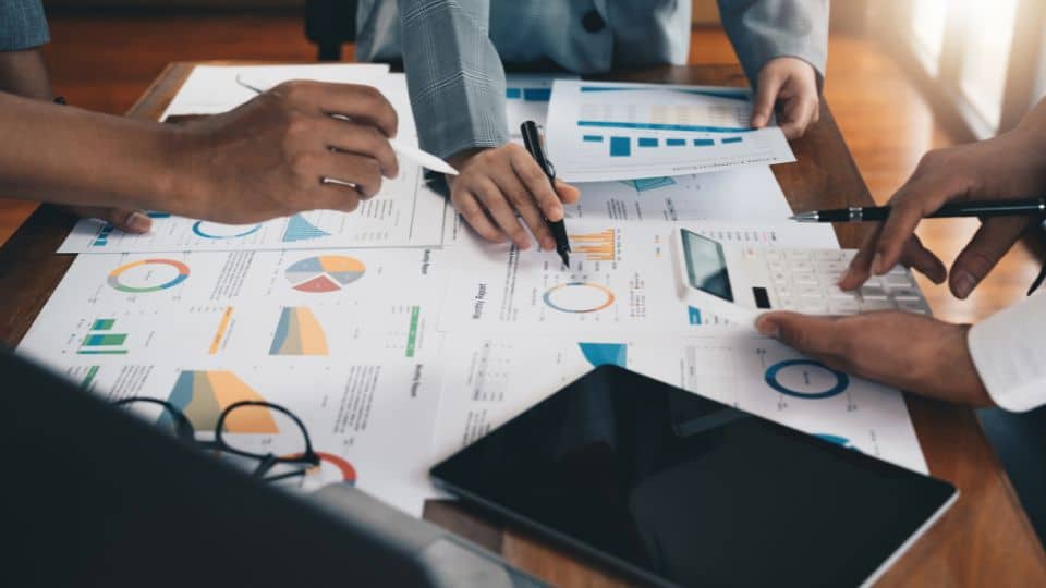 Business strategy papers spread out in a table with business owners hands pointing at them